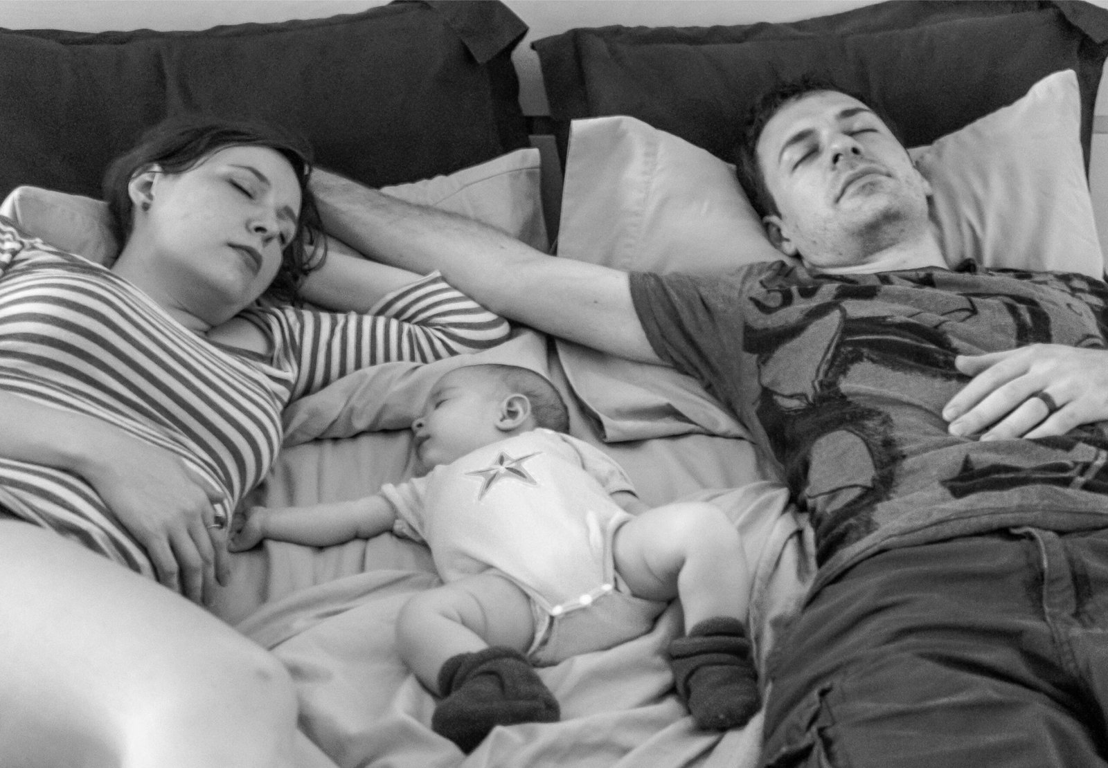 pareja en el sofá o en la cocina con gesto de agotamiento, bebé cerca